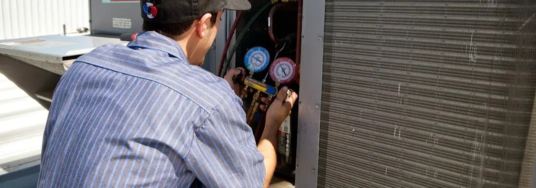 HVAC technician servicing a condenser unit in West Plains